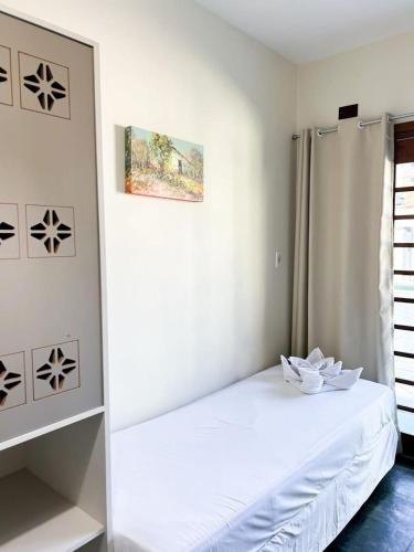 a bedroom with a white bed with a white flower on it at Hotel Cores do Mar in Bombinhas