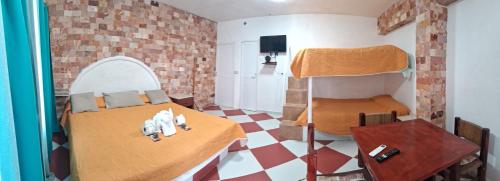 a room with a bed and a bunk bed with a table at Hotel Villas del Rey in Chachalacas