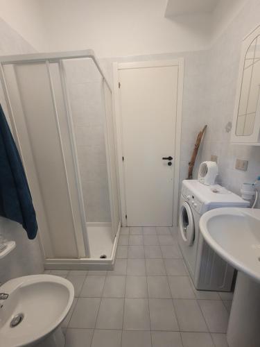 y baño con ducha y lavadora. en La Dolce Vita Apartment, en Marina di Strongoli