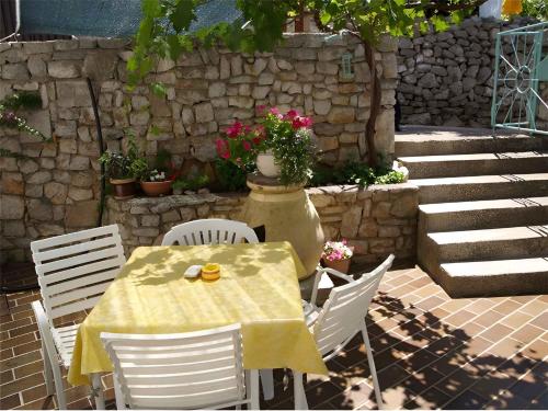 a table and chairs with a yellow table and flowers at Apartments in Veli Losinj 33624 in Sveti Nicola