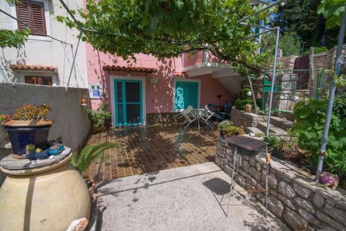 a pink house with a patio in front of it at Apartments in Veli Losinj 33624 in Sveti Nicola