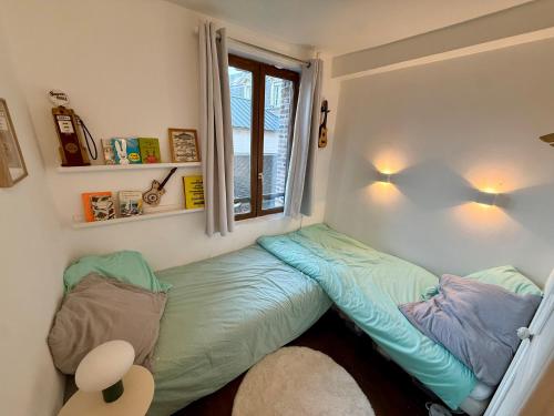 a small bed in a room with a window at Joli maison de pêcheur à 50m de la plage en plein centre in Étretat