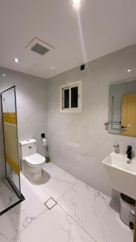 a white bathroom with a toilet and a sink at فندق رواف الفيصلية in An Naqāʼ
