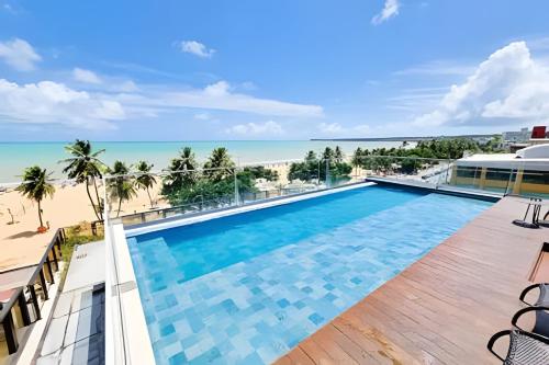 a view of the pool and beach from the balcony of a resort at Flat à beira-mar Infinity at the Sea - MyFlats Hospedagens in João Pessoa