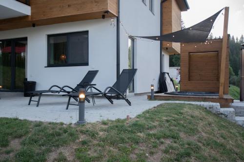 two chairs on a patio next to a house at Hyggemate - Nordic Villa with Sauna & Jacuzzi Retreat in Sarnitsa