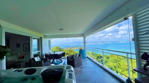 a room with a balcony with a view of the ocean at L'Ecrin de la Baie in Les Trois-Îlets