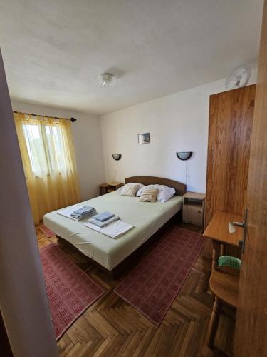 a bedroom with a bed and a desk and a window at Apartman Juliana in Stara Novalja