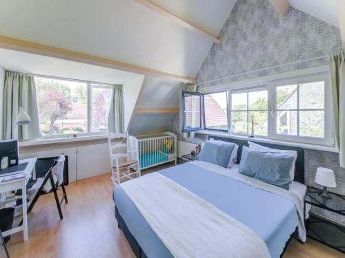 a bedroom with a bed and a desk and windows at Comfortable vacation home near the sea in Noordwijkerhout