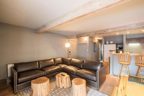 a living room with a leather couch and wooden stools at Lionshead Arcade with Fireplace & Close to Gondola in Vail