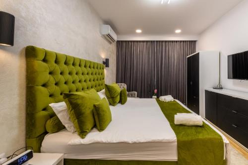 a bedroom with a large bed with a green headboard at Eden Central Boutique Suites - Garden & Spacious Apartments in Cluj-Napoca
