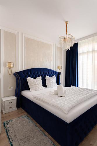 a large bed with a blue headboard in a bedroom at Sika Regal Apartment Arad - private garden & parking - self check-in in Arad