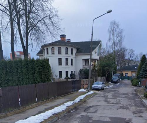 a white house with a fence and cars parked in a driveway at Baltā māja in Rīga