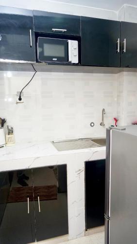 a kitchen with a sink and a microwave at Tériya House in Dakar