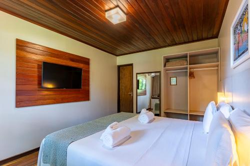 a bedroom with a white bed with a flat screen tv at Pousada Lua Bela in Fernando de Noronha