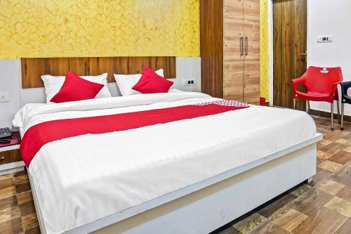a bedroom with a large white bed with red pillows at Hotel O CeeRock in Bhopal