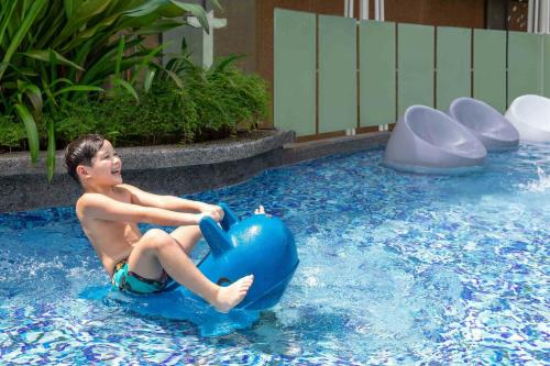 a young boy sitting on a blue ball in a swimming pool at Sheraton Manila Hotel at Newport World Resorts in Manila