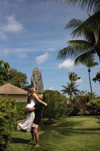 a bride and groom dancing in front of a rock at Pousada Lua Bela in Fernando de Noronha