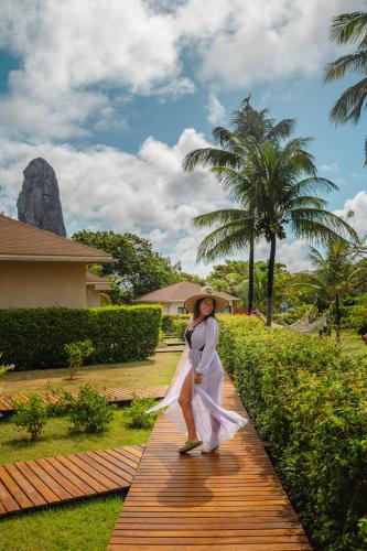 a woman walking down a wooden walkway with an umbrella at Pousada Lua Bela in Fernando de Noronha