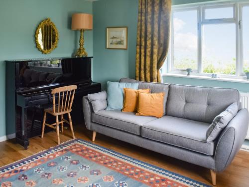 a living room with a couch and a piano at Heath View in Saxmundham