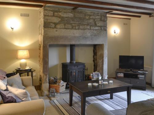 a living room with a stone fireplace and a table at Blue House Cottage in Elsdon