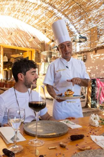 a man holding a plate of food next to a chef at Hotel Don Raul in San Pedro de Atacama