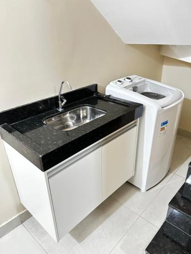 a kitchen with a sink and a washing machine at Studio Bougainville Apart in Conceição do Mato Dentro