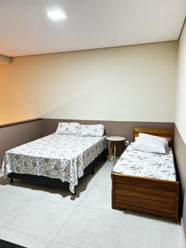 a bedroom with two beds and a table at Studio Bougainville Apart in Conceição do Mato Dentro
