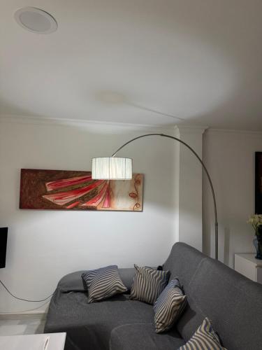 a living room with a gray couch and a lamp at Apartamento Los Pajaritos II in Jerez de la Frontera