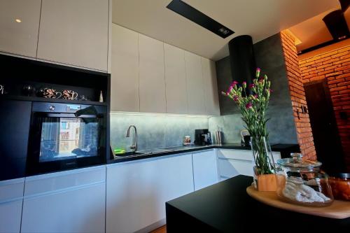 a kitchen with white cabinets and a vase of flowers on a table at Apartament na Mazurach in Ełk