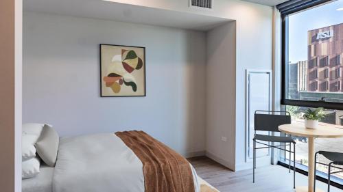 a bedroom with a bed and a table and a window at Sentral Sol Modern in Phoenix