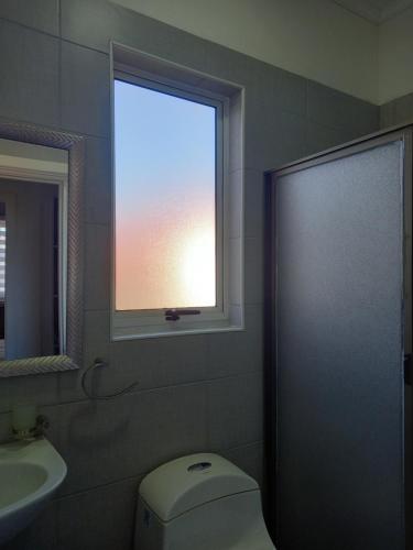 a bathroom with a window and a toilet and a sink at Hostal Cobquecura Bed & Breakfast in Cobquecura