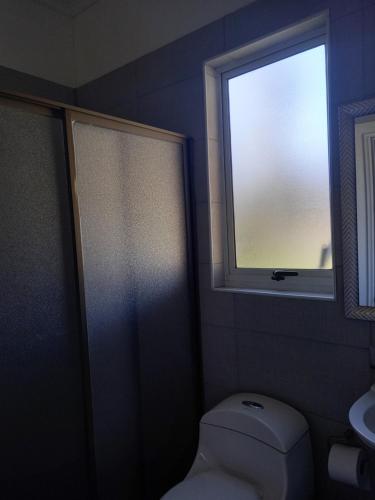 a bathroom with a toilet and a window at Hostal Cobquecura Bed & Breakfast in Cobquecura