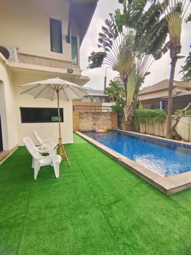 a yard with a pool and a lawn with an umbrella at Baan Natcha Villa in Pattaya Central