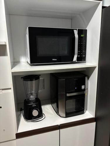 a kitchen with a microwave and a blender on a shelf at Unidades mobiliadas em condomínio in Lucas do Rio Verde