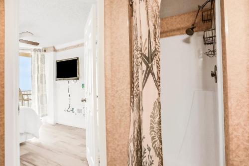 a bathroom with a shower curtain and a television at Oceania Plaza 509 in New Smyrna Beach