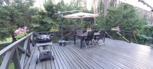 eine Holzterrasse mit Grill und Tisch mit Sonnenschirm in der Unterkunft Domek letniskowy nad jeziorem, Mazury in Teerau
