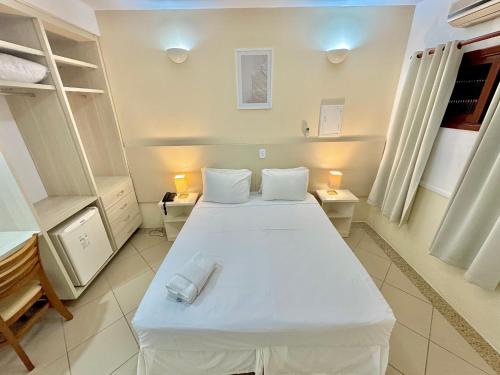 a bedroom with a large white bed with two lamps at Hotel Recanto dos Pássaros in São Sebastião