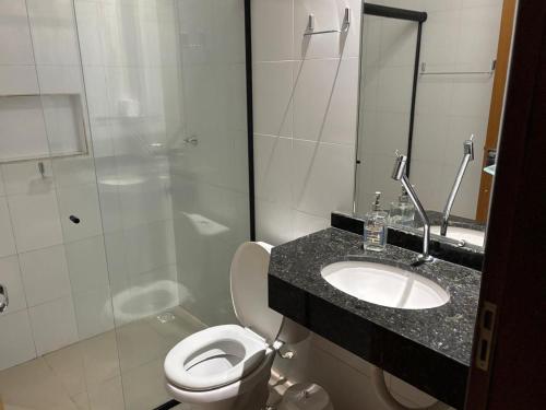 a bathroom with a toilet and a sink and a shower at Unidades mobiliadas em condomínio in Lucas do Rio Verde