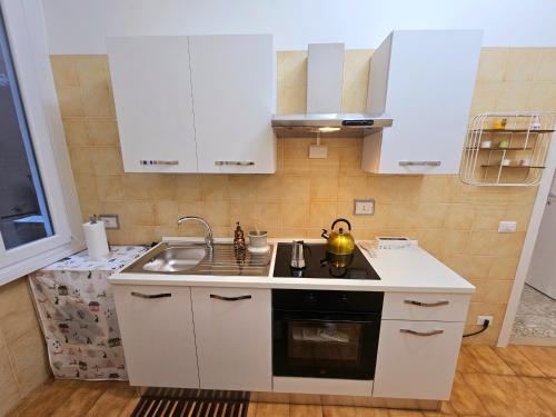 a kitchen with white cabinets and a sink at Costantino Imperatore Apt in Rome