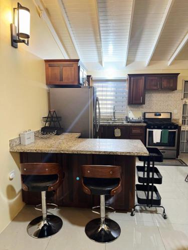 a kitchen with a counter with bar stools and a refrigerator at L&V Paradise Vacation Home with Pool and Gym in Falmouth