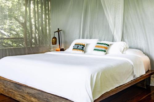 a white bed with pillows on it in a bedroom at La Loma Jungle Lodge and Chocolate Farm in Bocas del Toro