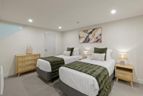 ein Schlafzimmer mit zwei Betten und einer Kommode mit zwei Lampen in der Unterkunft Stunning Lakefront 2-bed 2-bath with lake views in Queenstown