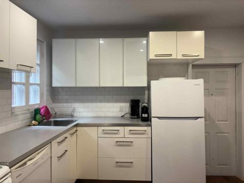 a kitchen with white cabinets and a white refrigerator at Spacious apartment in dowtown Montreal in Montréal
