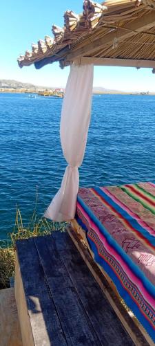 a pair of beds under a umbrella on the water at Titicaca villa del sol in Uros