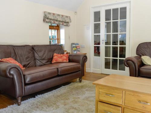 Una sala de estar con un sofá de cuero y una mesa de café. en Trem Yr Ynys, en Betws-y-coed