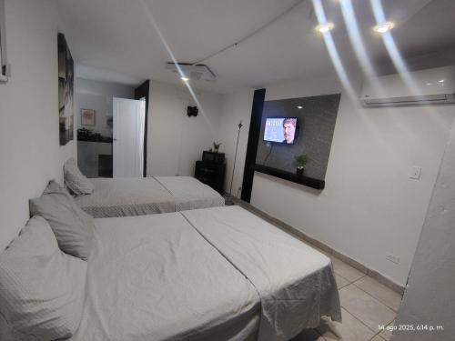 a bedroom with two beds and a tv on the wall at Duerme Relax 4 in Fajardo