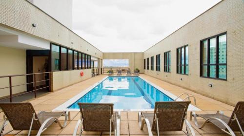 a swimming pool in a building with chairs around it at UH 406 - 3 Pessoas e garagem in Taguatinga