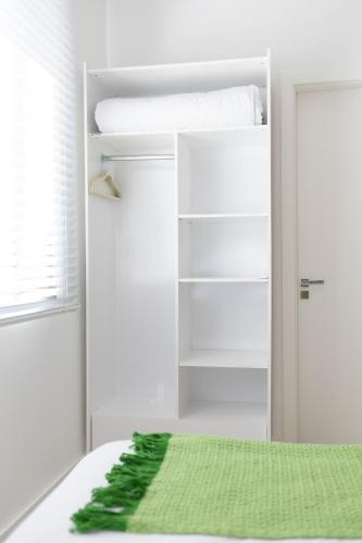 a white closet with a green blanket on a bed at Pousada Buona Serata in Bento Gonçalves