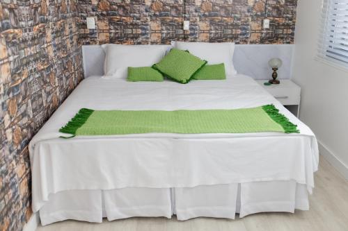 a bedroom with a white bed with green pillows at Pousada Buona Serata in Bento Gonçalves