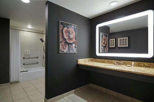 a bathroom with a sink and a mirror and a tub at Denver Marriott South at Park Meadows in Lone Tree